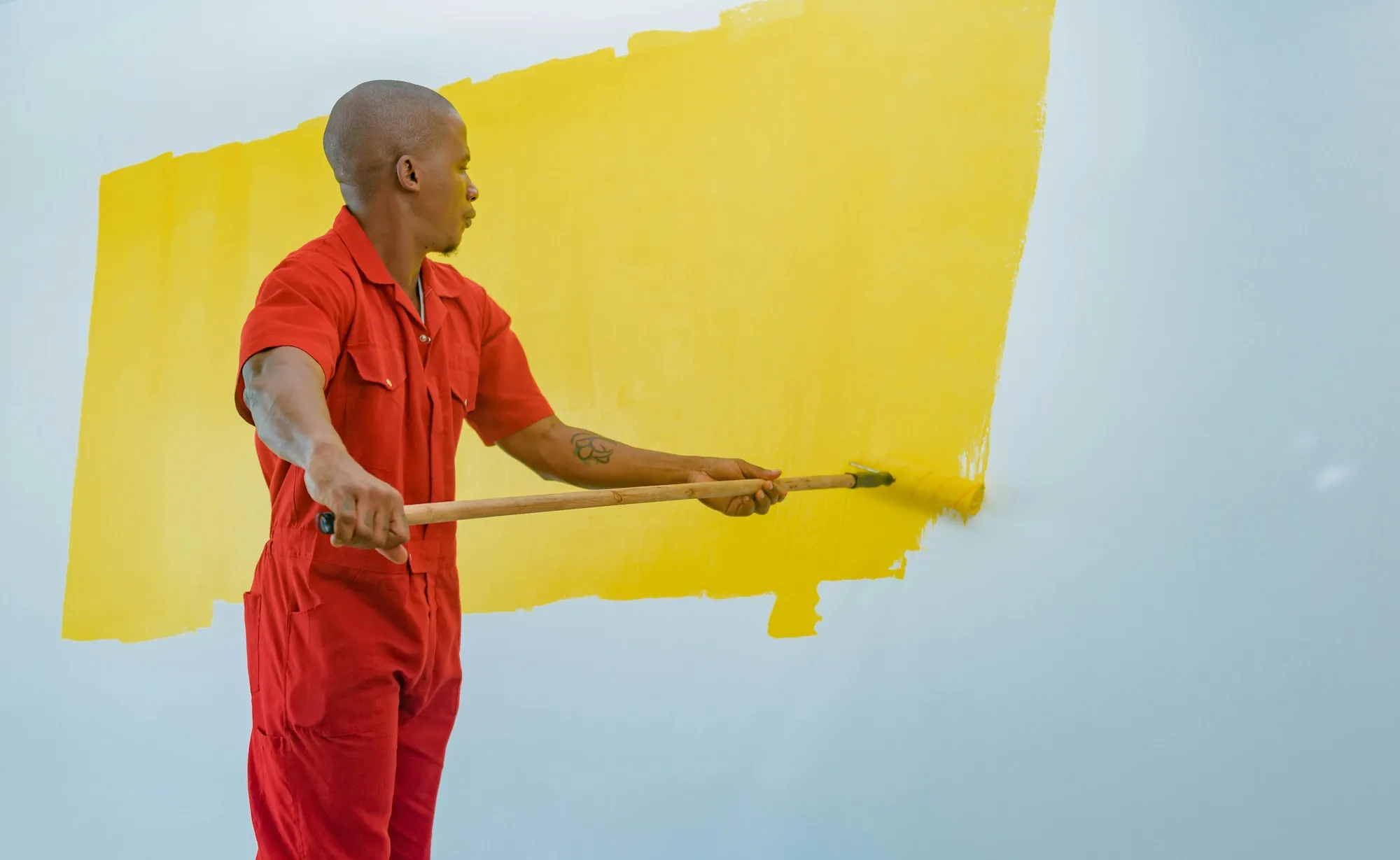 Painter rolling yellow paint onto a wall